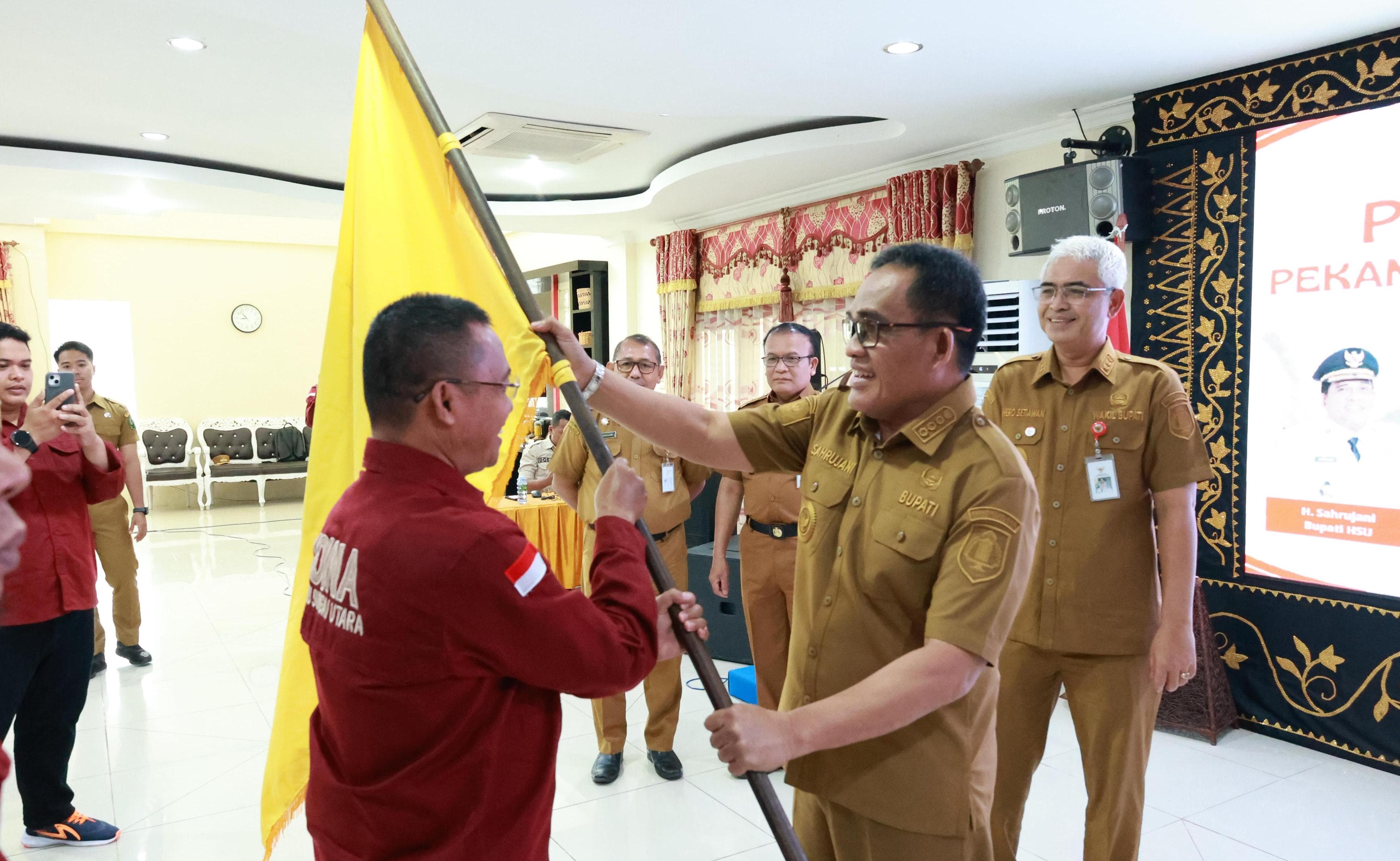 PATAKA:Bupati Kabupaten HSU, H Sahrujani menyerahkan pataka kontingen HSU kepada Ketua SOIna HSU, Faturahman dalam pelepasan atlet SOlna di Mes Negara Dipa, Selasa (8/7/2025).