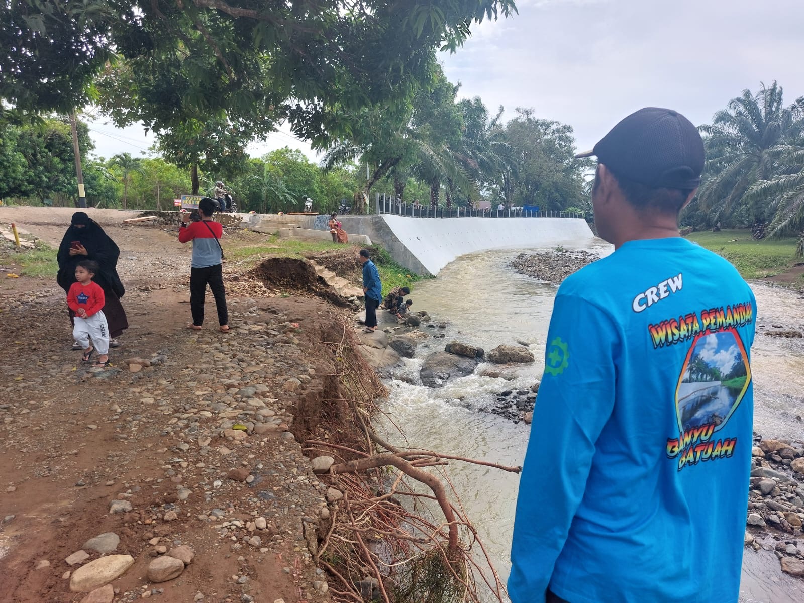 Ketua Pokdarwis Pemandian Mekar Banyu Batuah, Syahriansyah menunjukkan tebing dirusak banjir bandang. (Norsalim Yahya/Radar Banjarmasin)