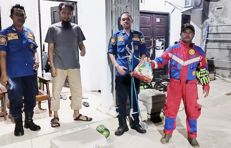 MENANGKAP: Damkar Banjarbaru berhasil menangkap ular yang sembunyi di belakang mesin cuci.