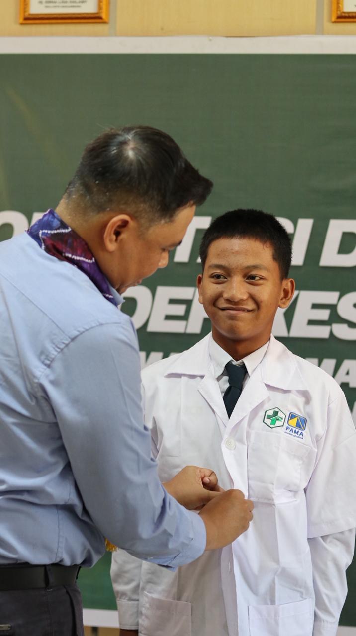 KADER: BBSO Head PT PAMA, Arif Cahyadi secara simbolis memakaikan jas kepada kader kesehatan remaja sebagai tanda dimulainya orientasi.