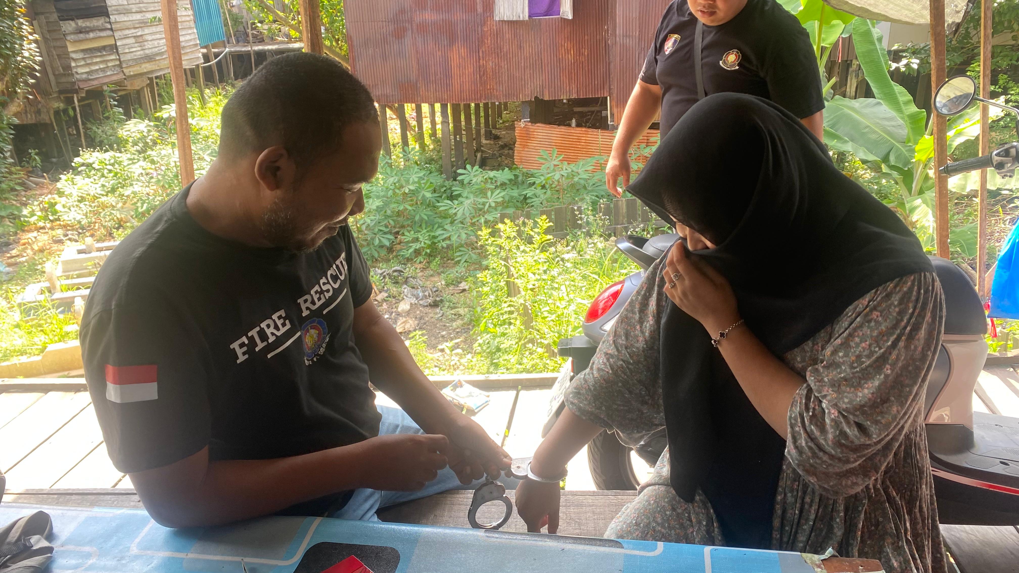 LEPAS BORGOL: Anggota Damkar HSU Edy Saputra berupaya melepas borgol dari tangan Riska (15) tahun, warga Desa Patarikan, Kecamatan Banjang, Jumat (1/8/2025).