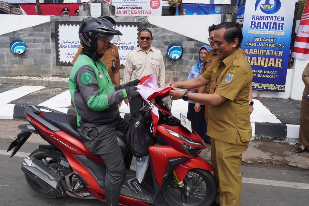 HUT RI:DKISP dan Disdukcapil Kabupaten Banjar membagikan bendera Merah Putih kepada pengguna jalan di Martapura, Selasa (5/8/2025).(Foto:DKISP DAN DISDUKCAPIL BANJAR)