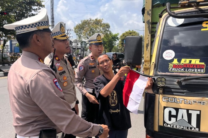 MERAH PUTIH: Kasat Lantas Polresta Banjarmasin Kompol Edwin W. Dirotsaha P. bersama Wakasat AKP R. Djoko dan Kanit Kamsel Ipda Ansyah Bhakti Satyabharda membagikan bendera merah putih kepada sopir.