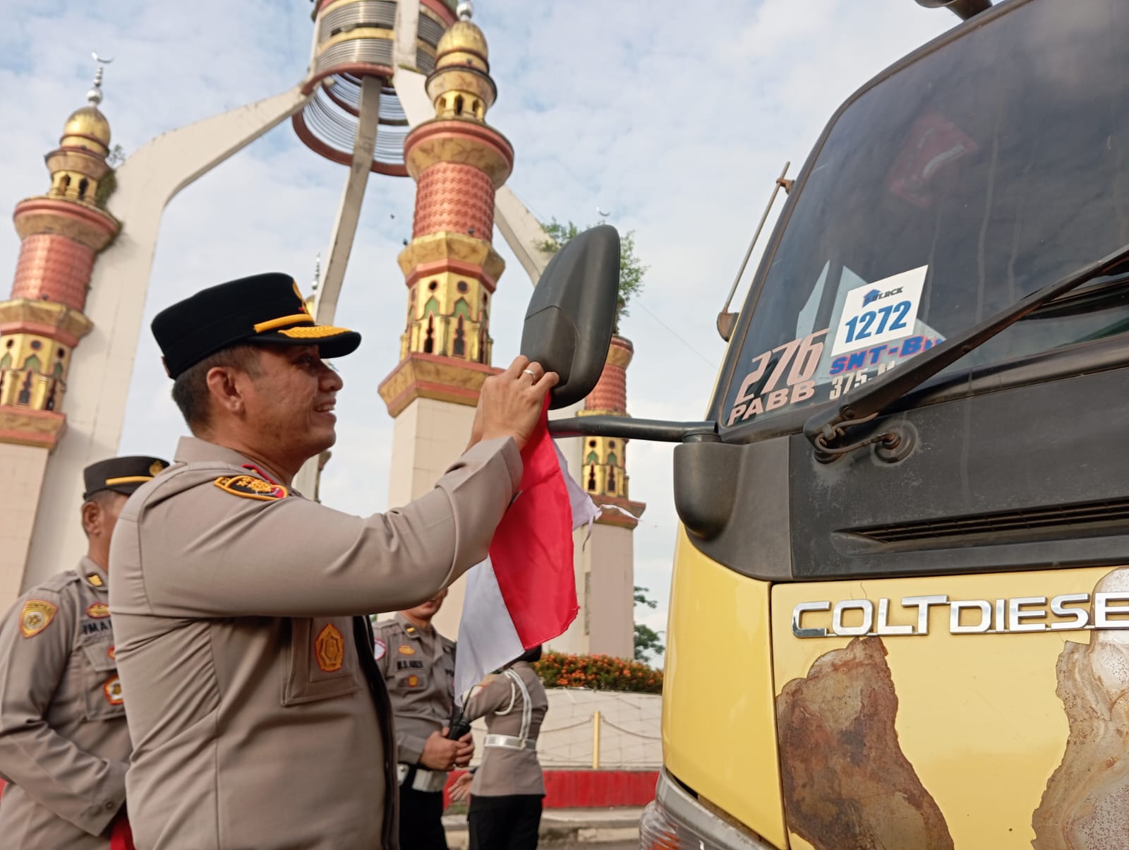 MEMBAGIKAN: Kapolres Tapin AKBP Weldi Rozika memasangkan bendera merah putih ke pengendara yang lewat di Bundaran Dulang.