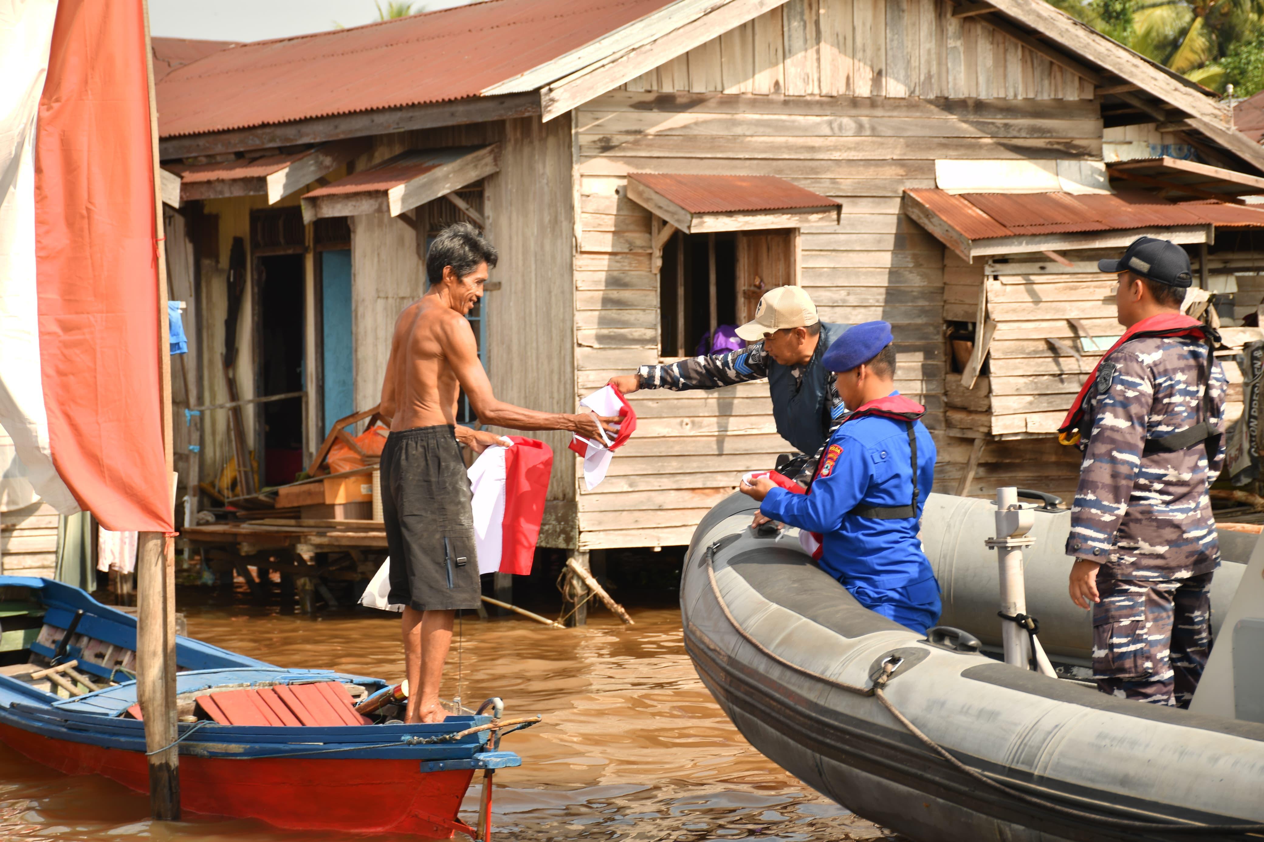 MERAH PUTIH:Prajurit Lanal Banjarmasin bersama Polri membagikan bendera kepada warga pesisir.