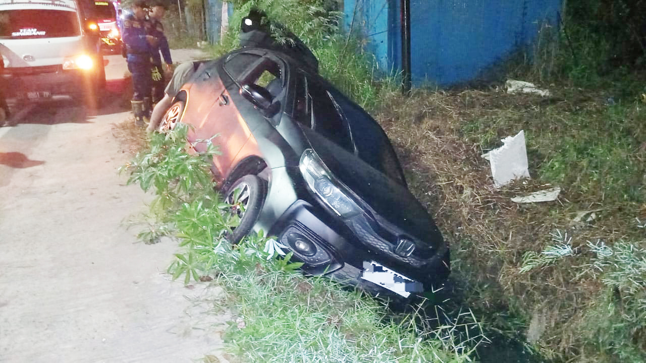 TERPEROSOK: Petugas Damkar Banjarbaru saat mengevakuasi mobil yang terperosok ke parit, Senin (11/8) dini hari.