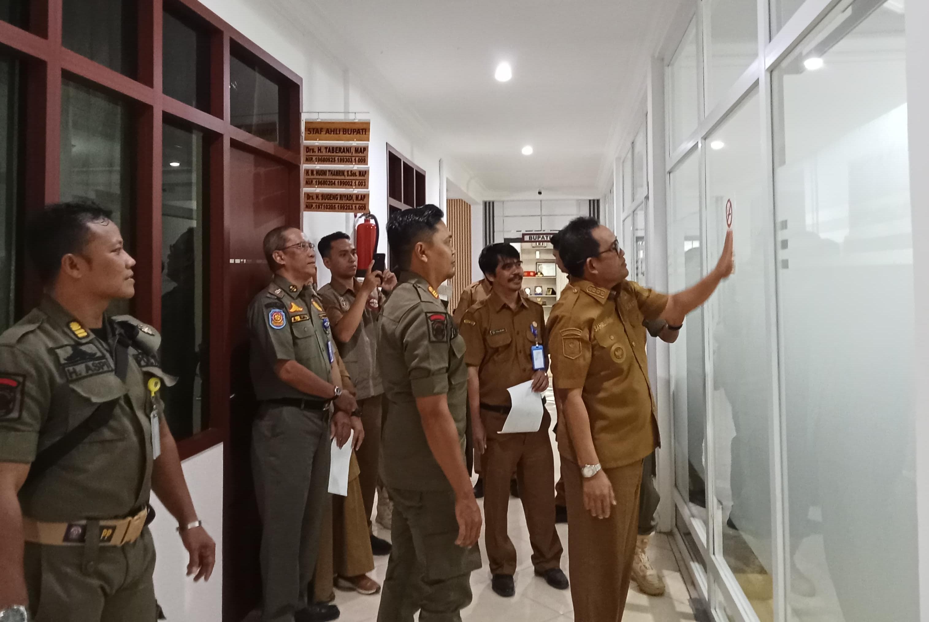 DUKUNGAN: Bupati Kabupaten HSU H Sahrujani, bersama Dinkes, Dinas Satpol PP dan Damkar HSU, memasang stiker KTR di Ruang Protokol Setda HSU. (Foto: M.Akbar/Radar Banjarmasin)