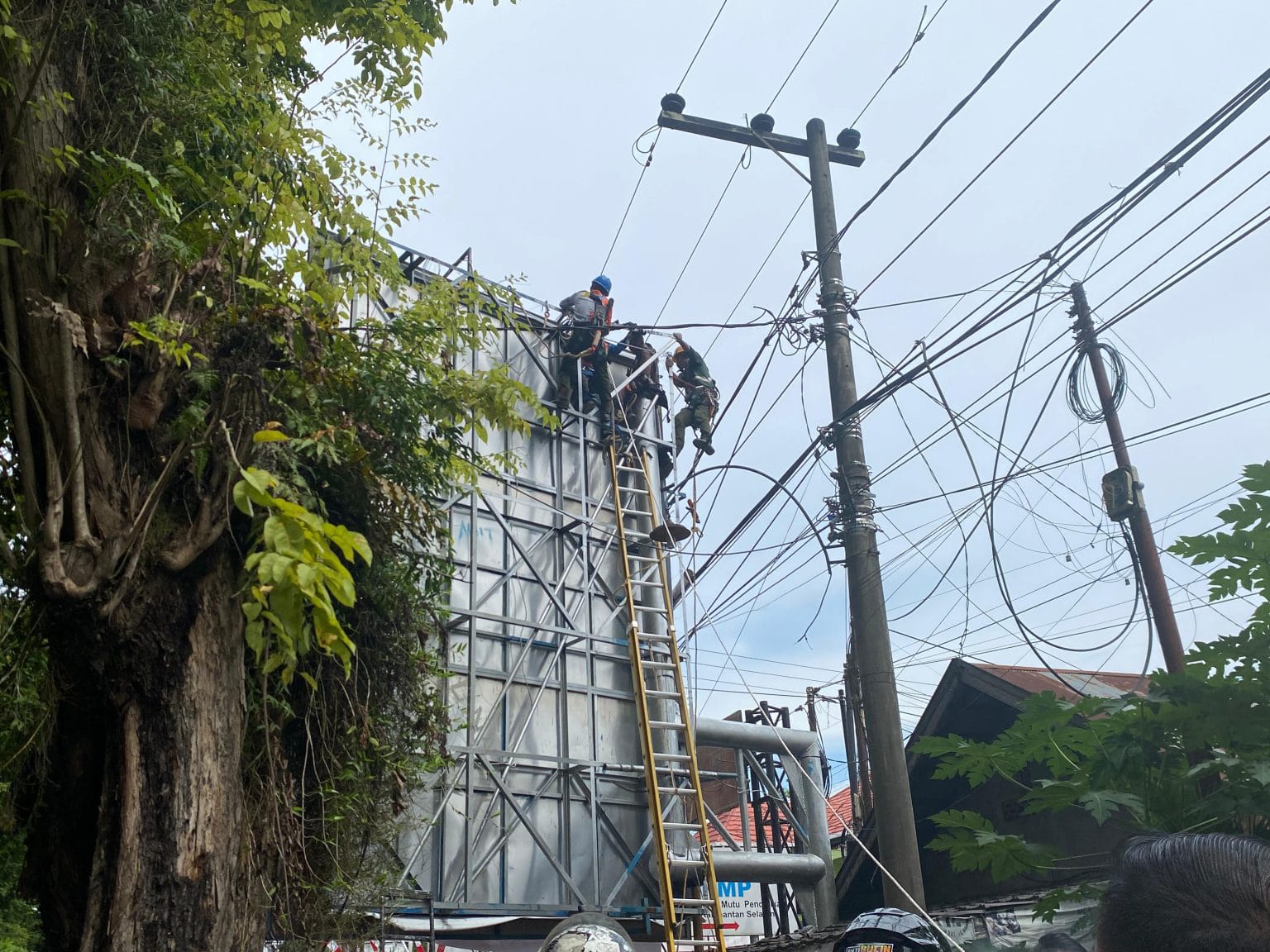 INSIDEN: Seorang pekerja tersetrum listrik saat mengganti baliho di papan reklame.
