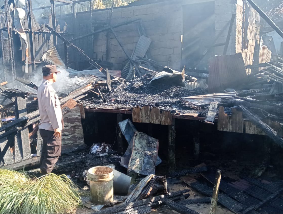 TINGGAL PUING: Seorang anggota Polres Tabalong sedang berada di antara puing kebakaran rumah Rusmadi.