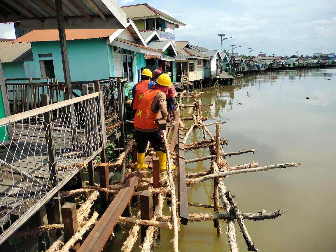 PENGERJAAN: Sejumlah pekerja tengah sibuk memasang pondasi dan sebagian lagi memasang papan lantai titian.