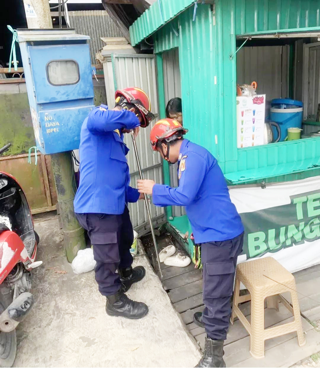 MEMBANTU: Petugas Damkar Banjarbaru membantu mengambil kunci motor milik seorang warga yang jatuh ke dalam selokan.