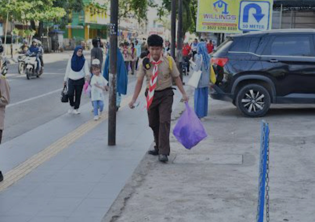 KUMPULKAN SAMPAH: Seorang pramuka muda terlihat serius mengumpulkan sampah di sepanjang jalur jalan sehat.