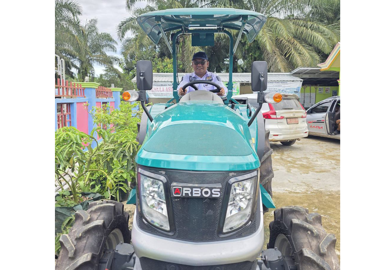 SENANG: Wakil Ketua DPRD Kotabaru Awaludin mencoba duduk di traktor roda empat di sela-sela panen padi di Desa Bumi Asih, Kelumpang Selatan.