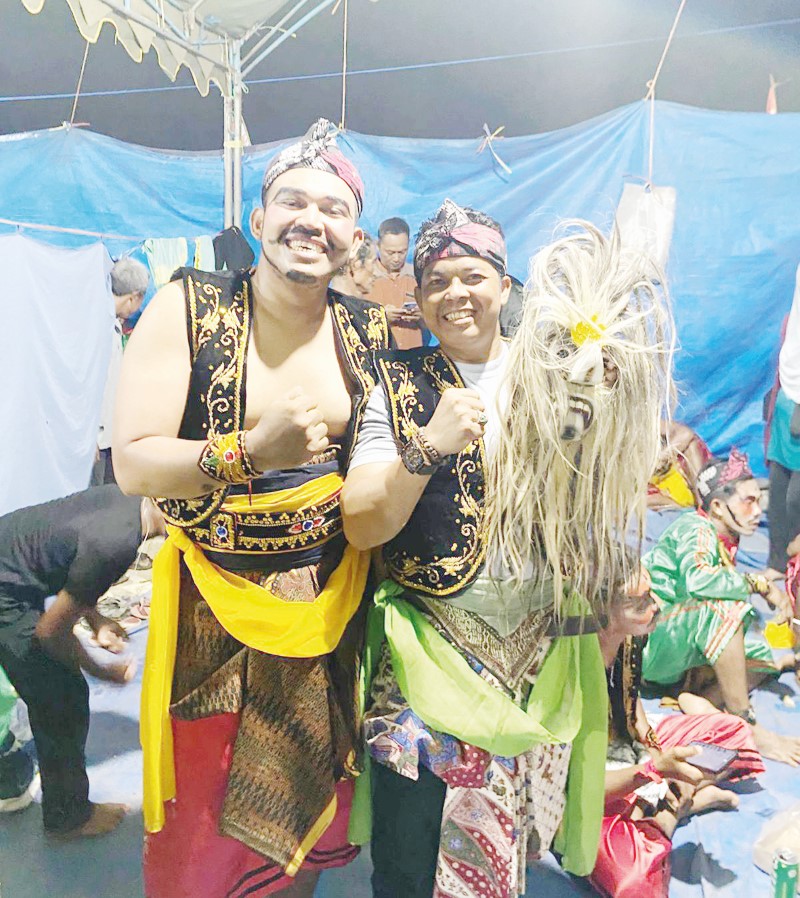 SENANG: Sambil memegang topeng Rahmad berfoto bareng seniman Prajuritan.