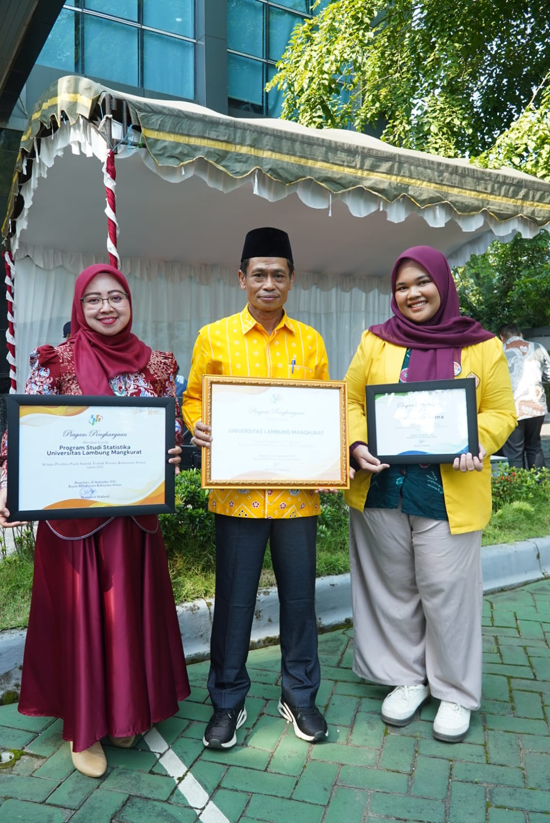MOMEN: Rektor ULM bersama dosen dan mahasiswa berfoto sambil memperlihatkan tiga penghargaan statistik yang diraih ULM dari BPS Kalsel.