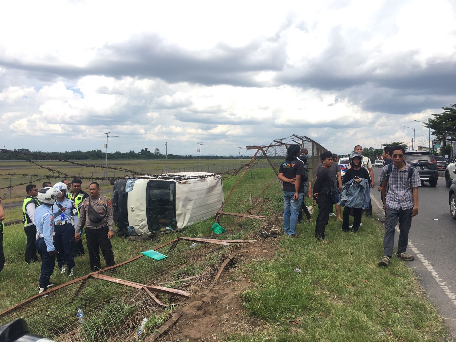 LAKA LANTAS: Mobil Gran Max terguling hingga melewati pagar pembatas antara jalan raya dengan kawasan Bandara Syamsudin Noor, Sabtu (27/9/2025) siang.