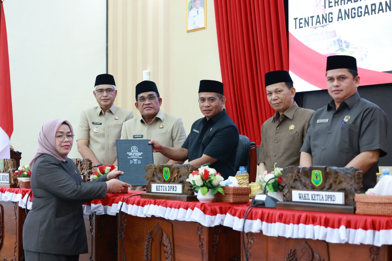 MENYERAHKAN: Juru bicara FKB HSU Ratna Sri Dewi saat menyerahkan pandangan umum FKB ke pimpinan DPRD HSU disaksikan Bupati HSU H Sahrujani, di Aula Paripurna Senin (13/10/2025).