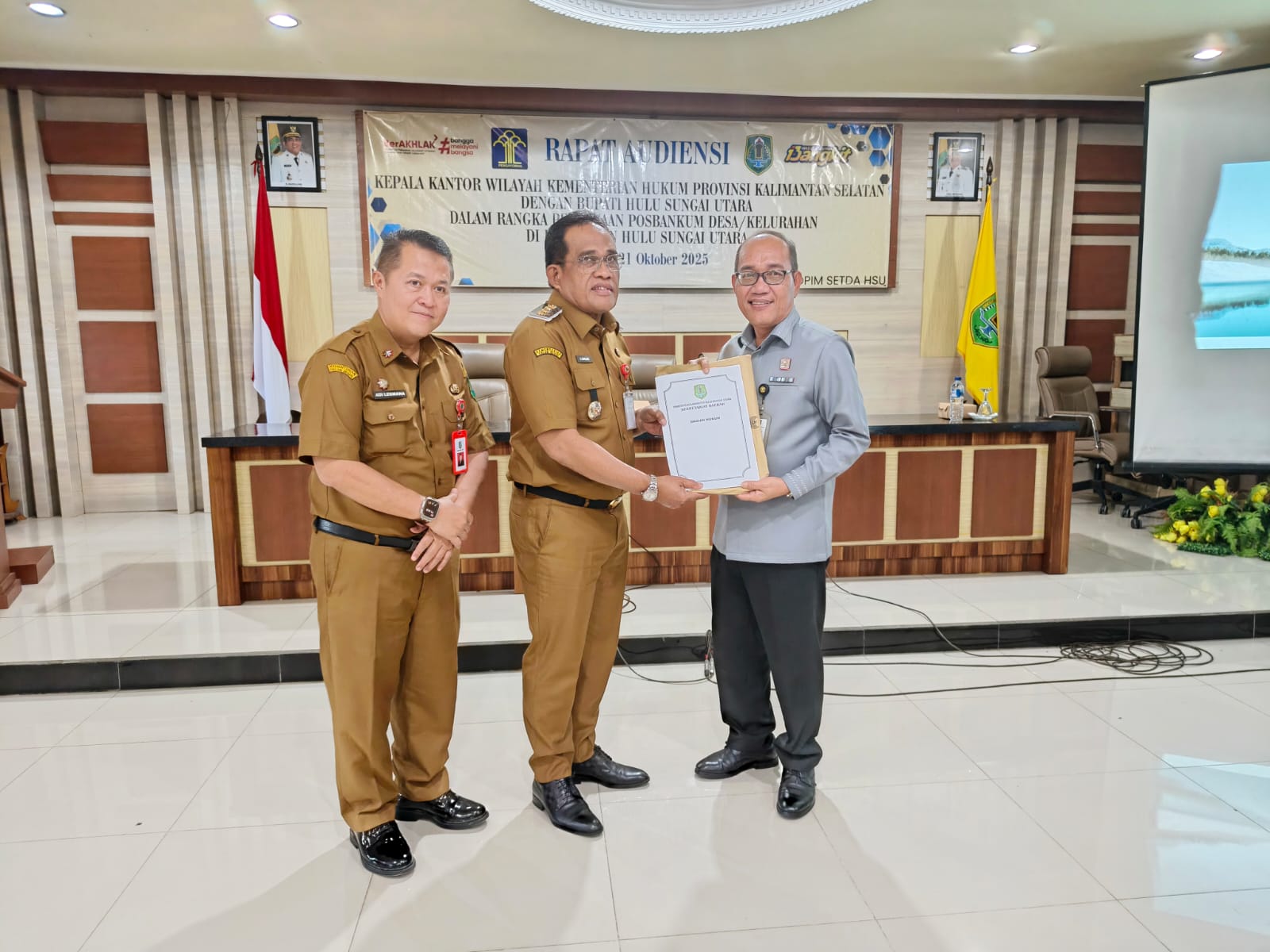 SINERGI:Kepala Kanwil Kemenkum Kalsel, Alex Cosmas Pinem menyerahkan Surat Tanda Registrasi Pos Bantuan Hukum (STR Posbankum) kepada Bupati HSU, H Sahrujani yang didampingi Sekda HSU, Adi Lesmana.