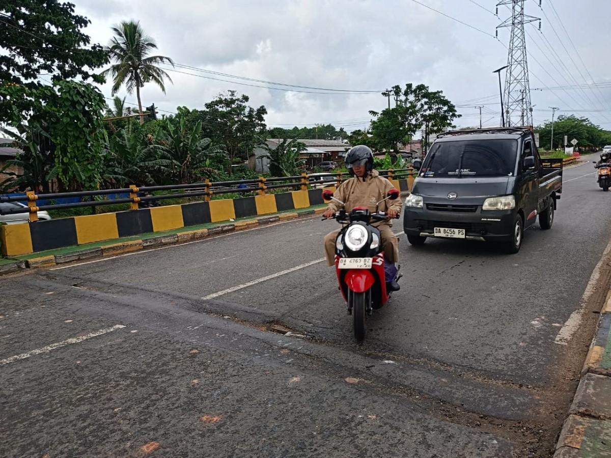 BERHATI-HATI - Pemotor terpaksa memelankan laju motornya saat melintas di atas sambungan jembatan yang rusak di Jembatan Guntung Manggis, Jumat (24/10).&nbsp;
