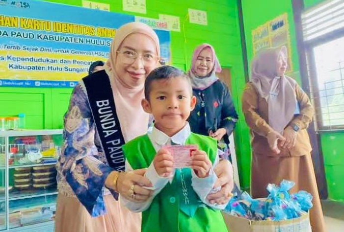 MOMEN:Bunda PAUD HSU, Hj Murniati Sahrujani saat menyerahkan Kartu Identitas Anak (KIA) di RA Al Ukhuwwah Amuntai, Senin (27/10/2025).