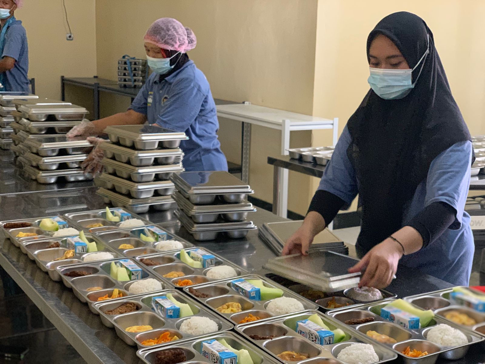 SIAP DISALURKAN: Petugas SPPG Yayasan Kemala Bhayangkari Polres Tanah Bumbu menyiapkan paket makanan untuk program Makan Bergizi Gratis. (Foto: Zulqarnain/Radar Banjarmasin)