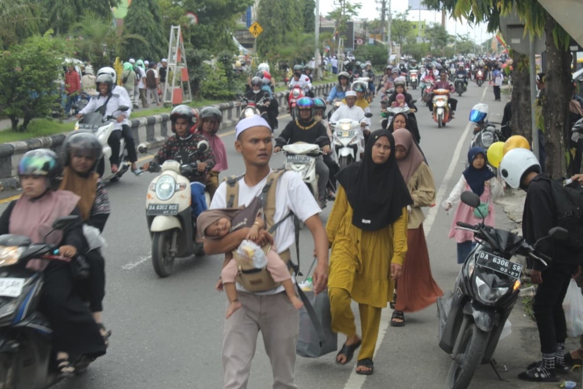 GENDONG ANAK : Salah satu jemaah saat mencari lokasi penginapan di sekitar kawasan Martapura saat Haul Abah Guru Sekumpul ke-19 pada awal Januari 2025 lalu.