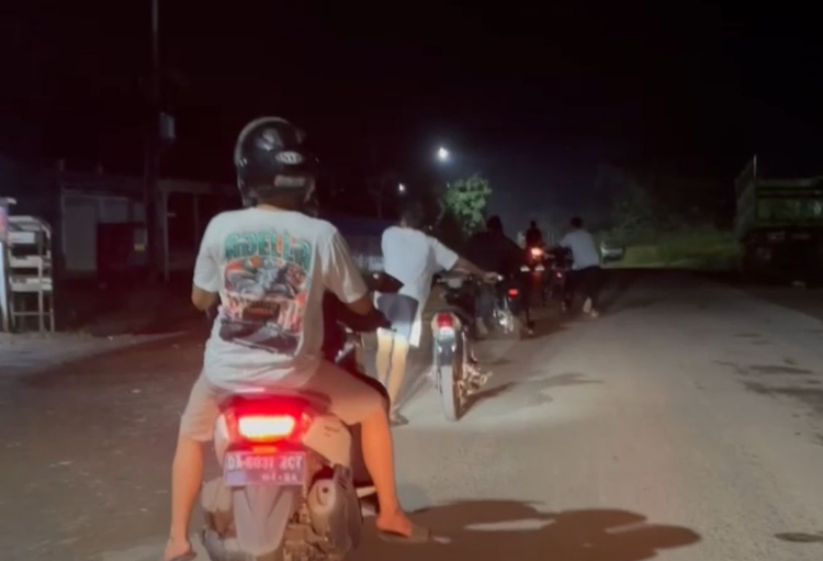 Para remaja mendorong sepeda motor menuju Mapolsek Satui usai terjaring razia balapan liar, Ahad dini hari (9/11).