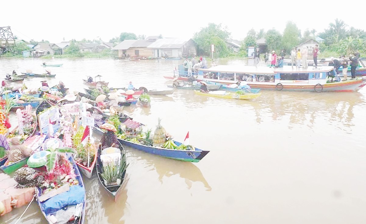 MENAWARKAN: Pedagang saat menawarkan hasil kebun dari atas perahu saat Festival Pasar Terapung Lok Baintan 2025.