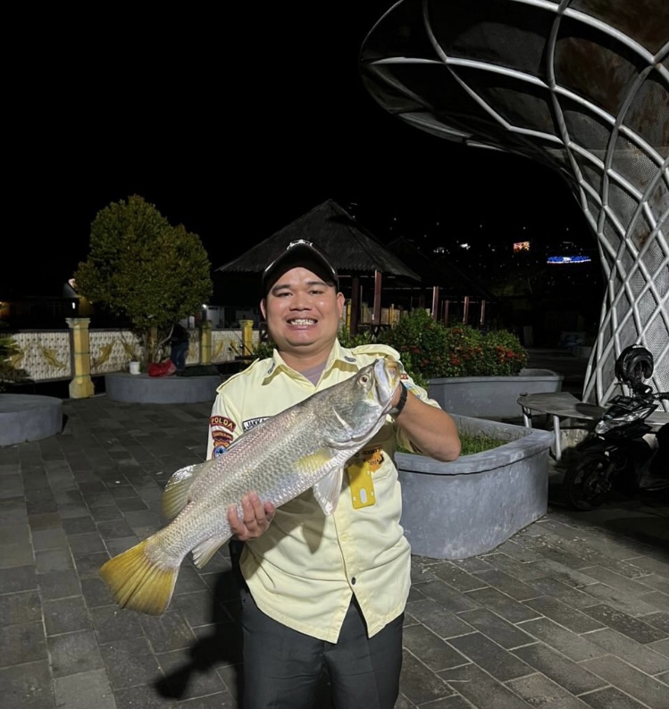 Strike! Satpam Siring Laut menunjukkan ikan kakap putih yang berhasil ditangkapnya.