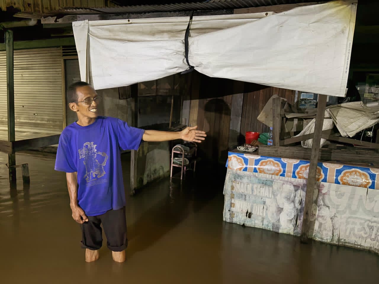 SIAGA:Abdul Basit memilih tetap terjaga selama banjir rob menggenang rumahnya di Jalan Pembangunan Ujung, Kuin Cerucuk, Banjarmasin Barat, Kamis (13/11/2025).