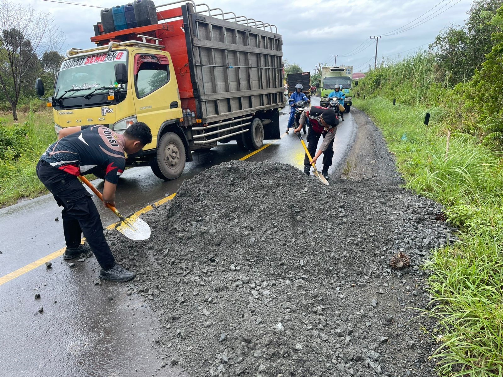 SWADAYA: Personel Satlantas Polres Batola dan Sat Samapta bergotong royong menguruk jalan dengan batu.