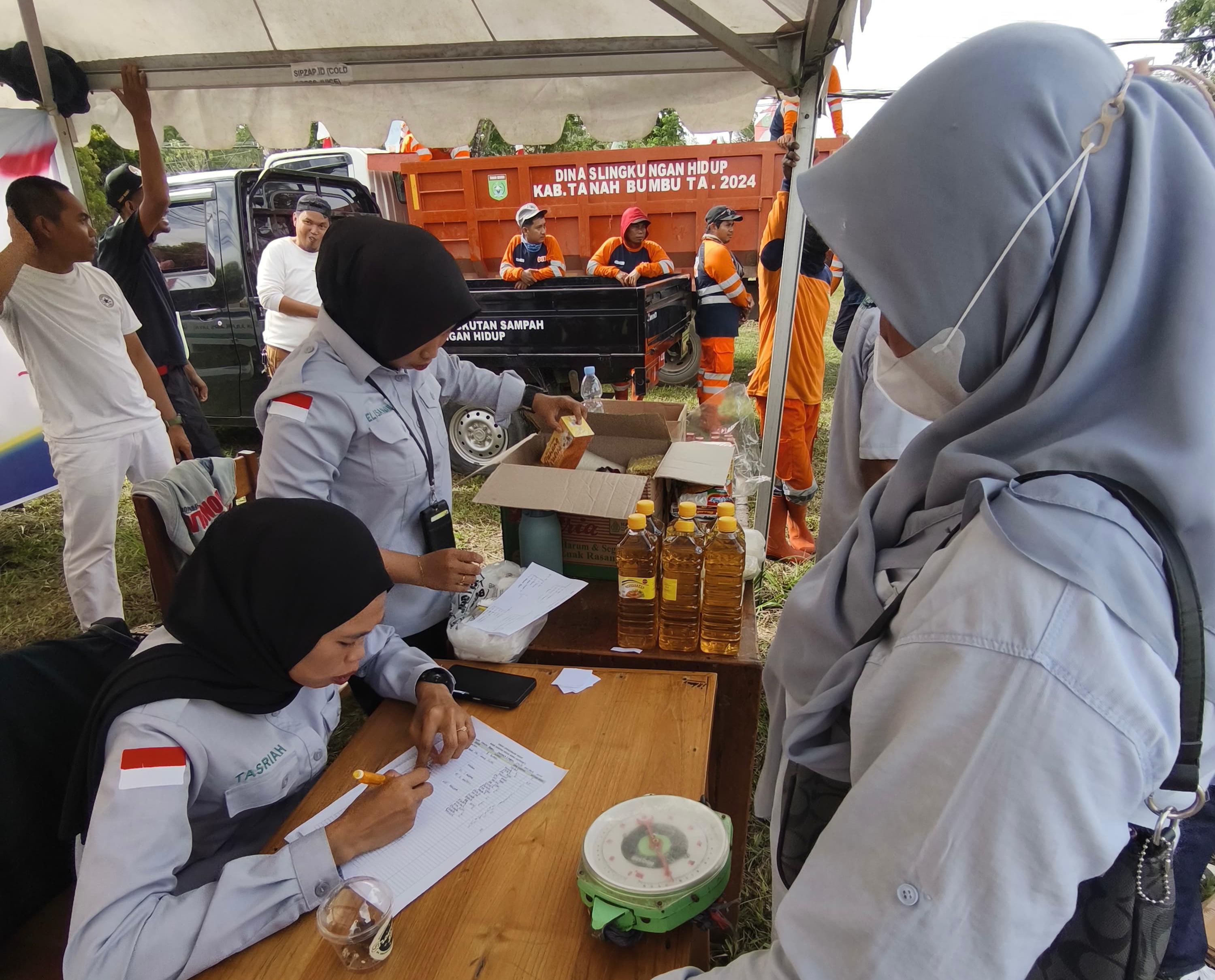 MENCATAT: Petugas DLH mencatat sampah anorganik yang ditukar warga dengan sembako pada kegiatan di Kecamatan Angsana. (Foto: Indah untuk Radar Banjarmasin)
