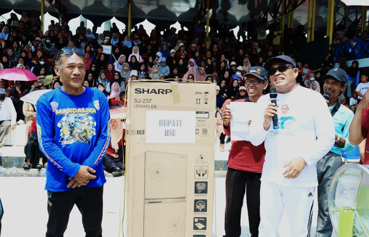 MOMEN:Bupati Kabupaten HSU, H Sahrujani (kanan) menyerahkan doorprize kepada peserta pemenang jalan sehat milad Muhammadiyah di Lapangan Pahlawan Amuntai, Minggu (16/11/2025).