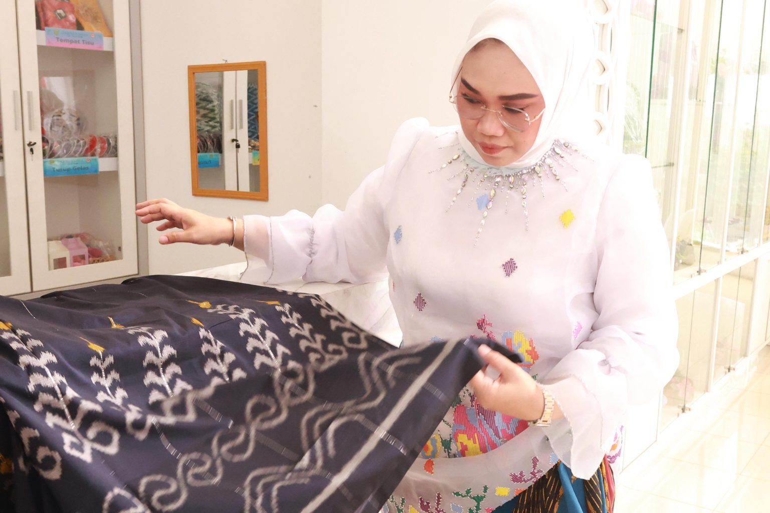 PERMINTAAN MELONJAK: Ketua Dekranasda Tanah Bumbu Andi Irmayani memperhatikan detail kain tenun Tanah Bumbu yang diproduksi perajin daerah.