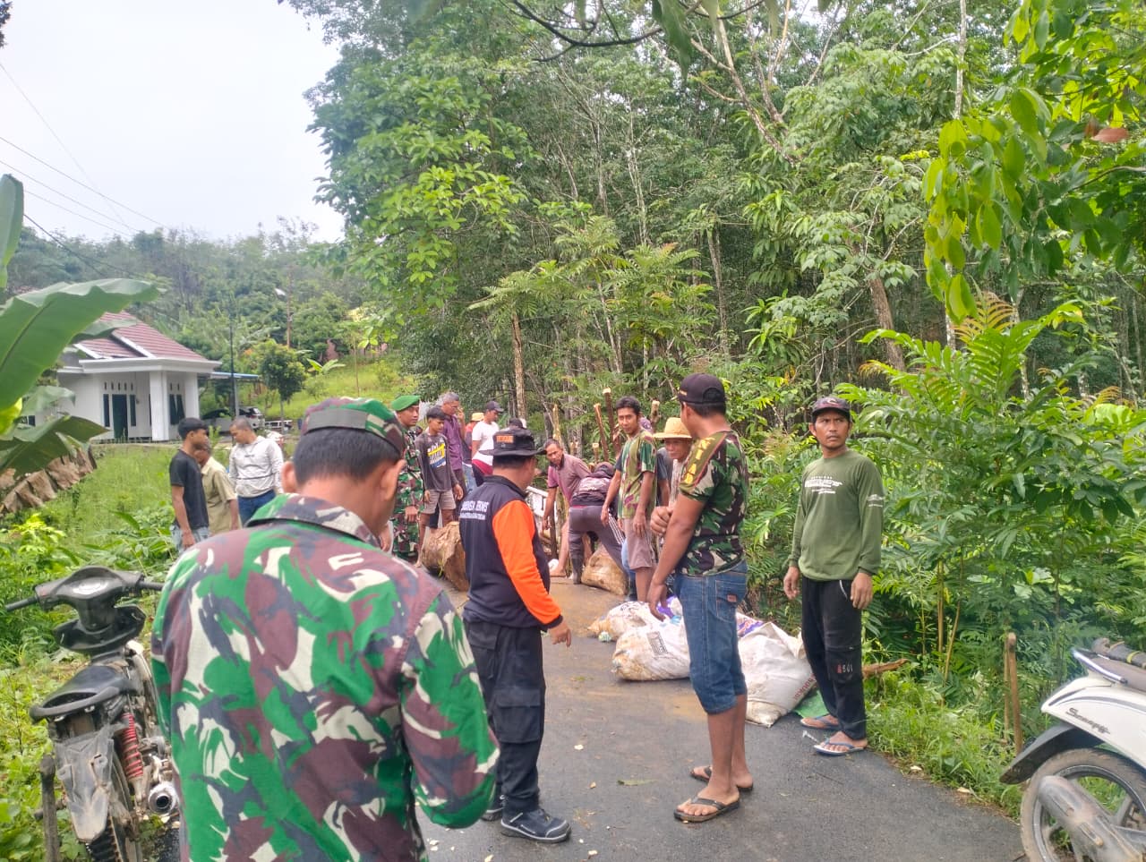 GOTONG ROYONG:BPBD Tapin bersama masyarakat memasang penanda tanah longsor Gunung Ulin agar warga berhati-hati melintas di jalan yang tergerus.