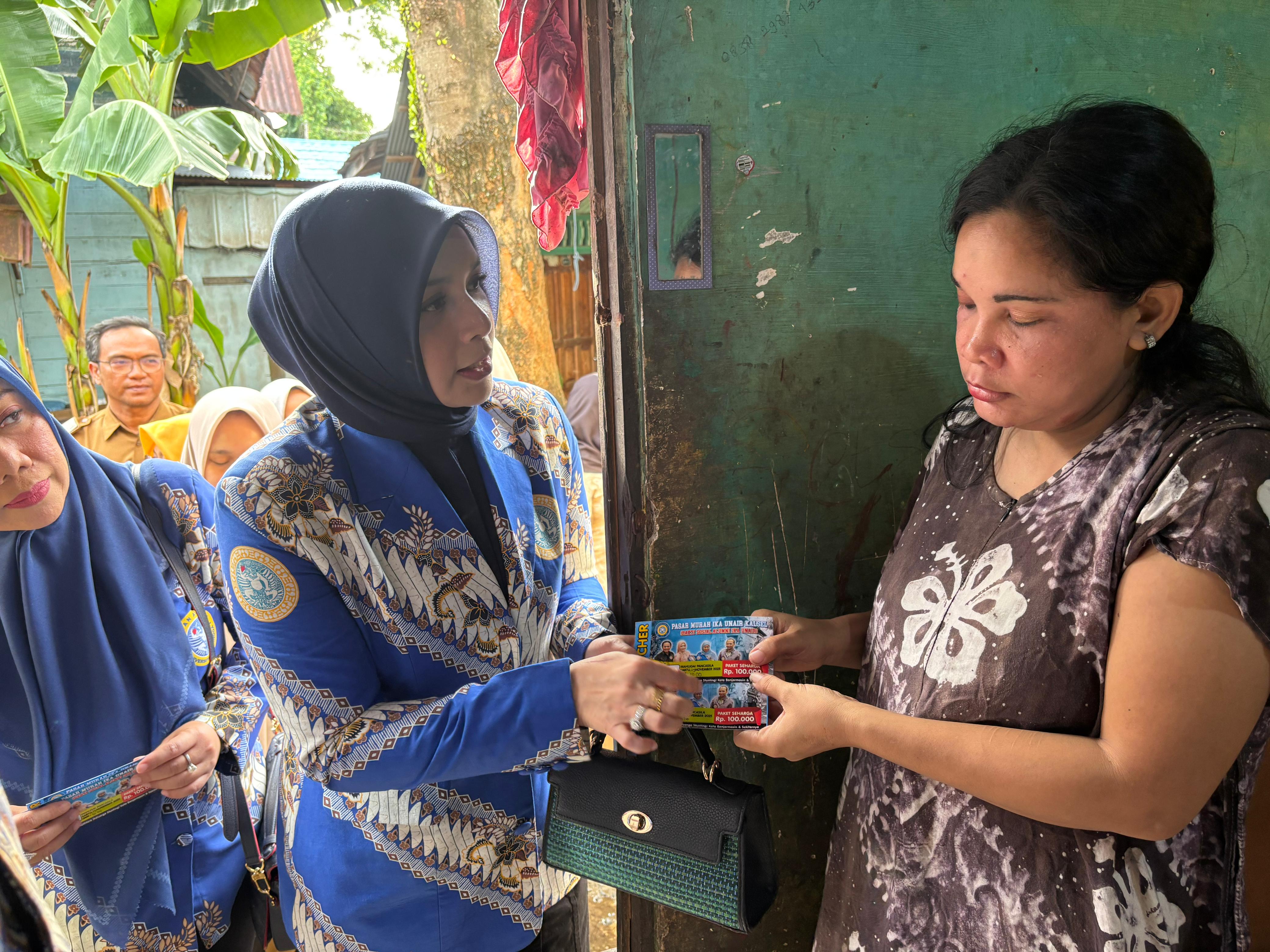 BERBAGI: Ketua IKA Kalsel, drg Ellyana Trisya Hasnuryadi menyerahkan voucher belanja gratis kepada keluarga penerima manfaat penderita manfaat di Kelurahan Pasar Lama. Selasa (25/11/2025).