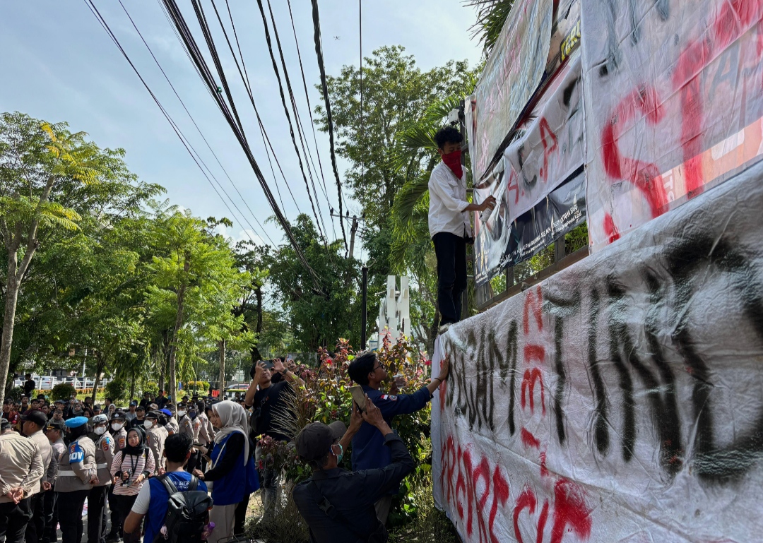 MENYORET: Massa aksi jilid II mulai menyoreti spanduk bergambar wajah pimpinan DPRD di depan Rumah Banjar, Rabu (27/11/2025).