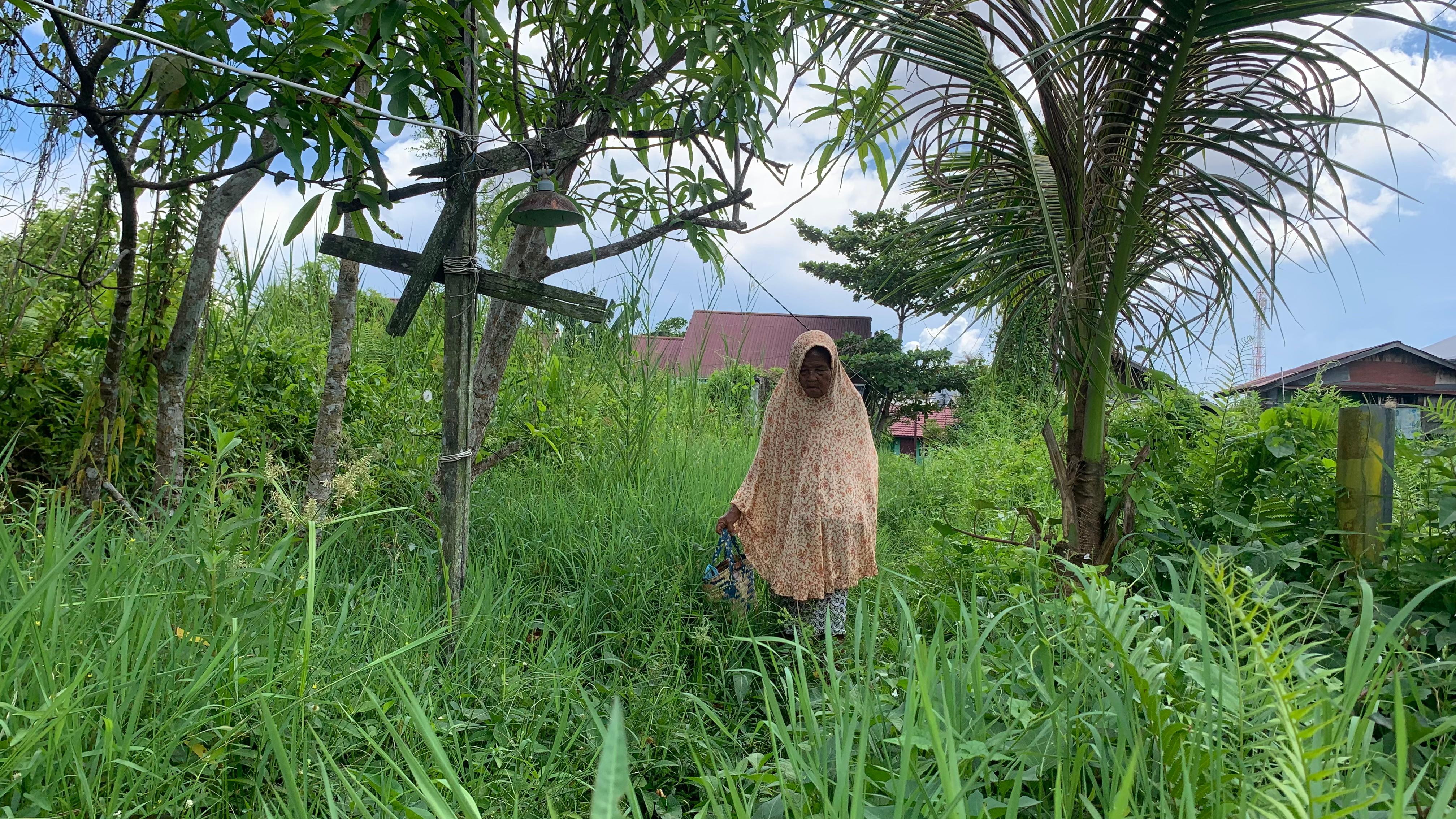 Nenek Saidah berjalan menyusuri semak belukar untuk sampai ke rumahnya di Jalan Sungai Miai Dalam, Banjarmasin Utara. (Zulvan Rahmatan/Radar Banjarmasin)