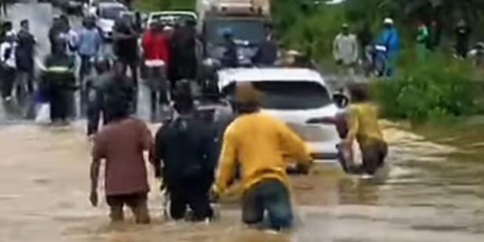 MOGOK: Sejumlah warga mendorong mobil yang mogok saat melintasi genangan banjir di Desa Alimukim, Pengaron, Senin (8/12/2025).