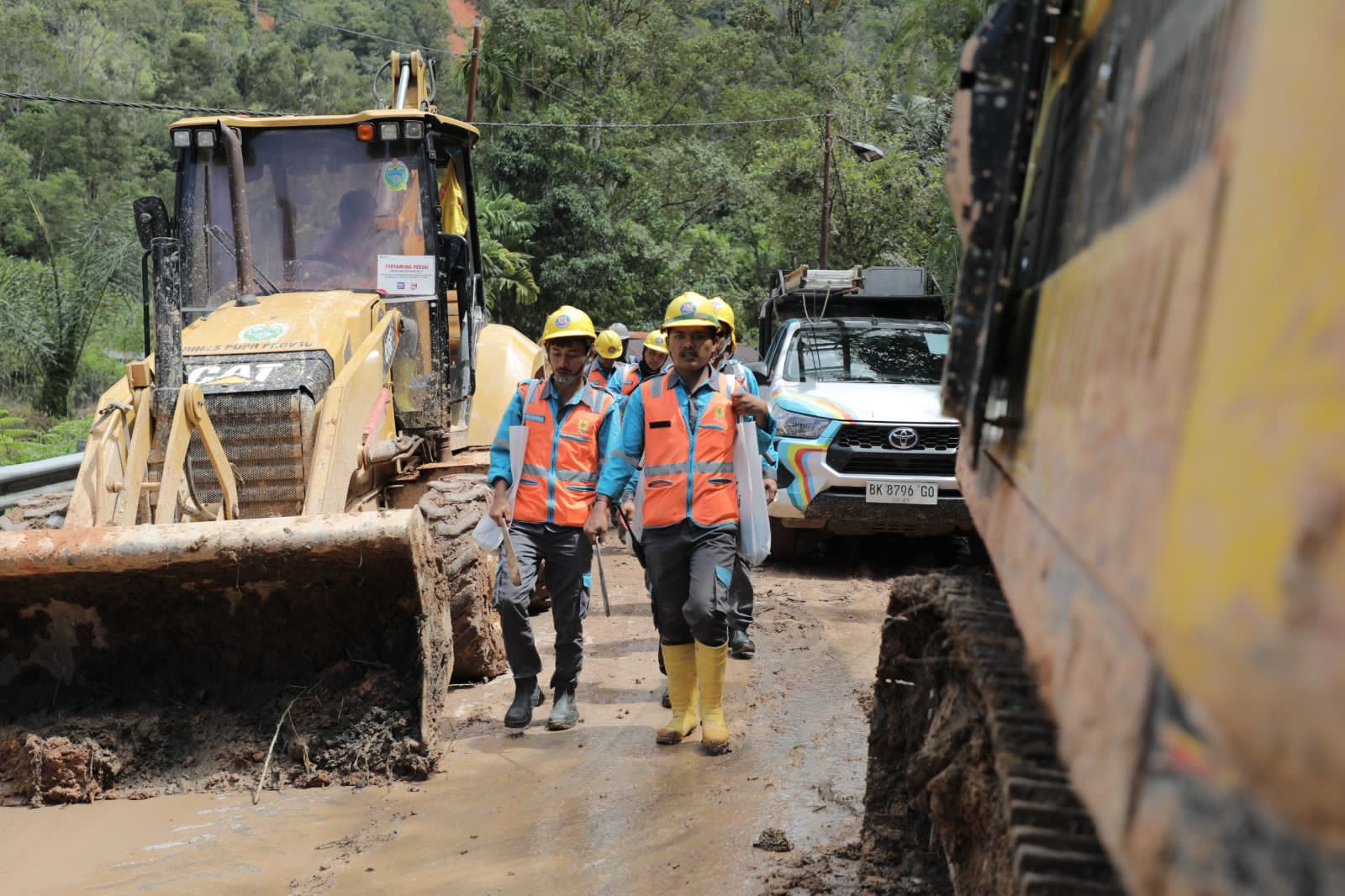 WILAYAH TERISOLASI:Petugas PLN menyusuri jalur berlumpur menuju titik terdampak di Adian Koting, Tapanuli Utara.