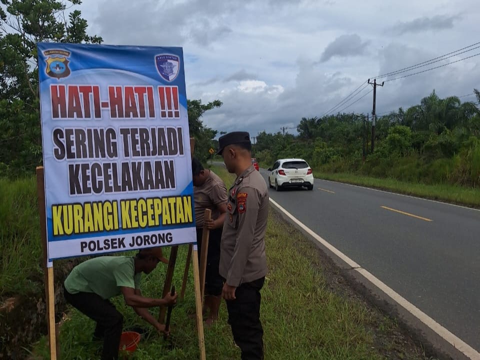 EDUKASI : Personel Polsek Jorong saat memasang spanduk di daerah rawan kecelakaan di Jalan A Yani, Kecamatan Jorong, Selasa (16/12).