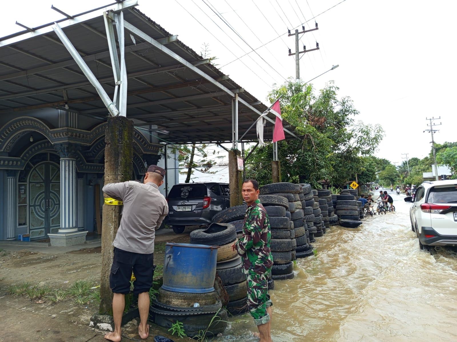 BANJIR: Aparat memasang police line di Jalan Poros Amuntai-Balangan di Kecamatan Banjang Kabupaten HSU yang kebanjiran.