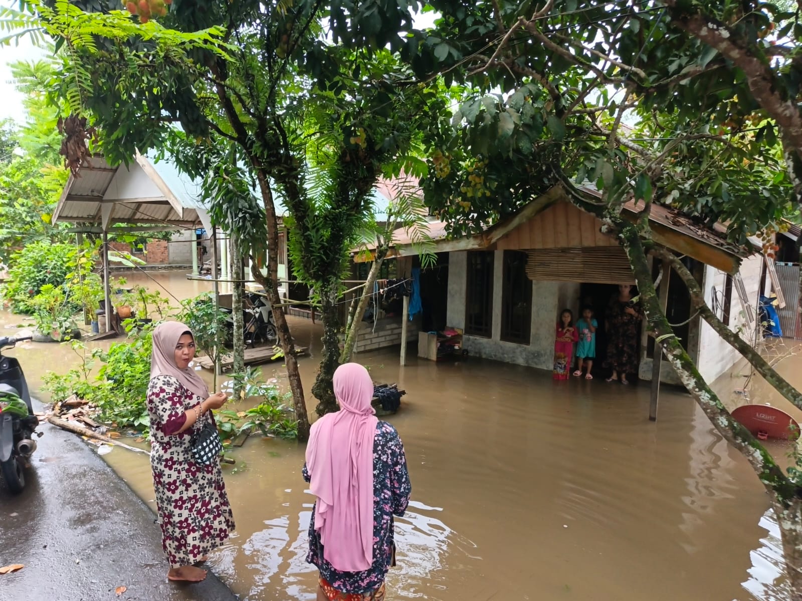 BERTAHAN: Warga terdampak banjir bertahan di rumah masing-masing saat genangan air masih merendam lingkungan mereka, Rabu (17/12/2025).