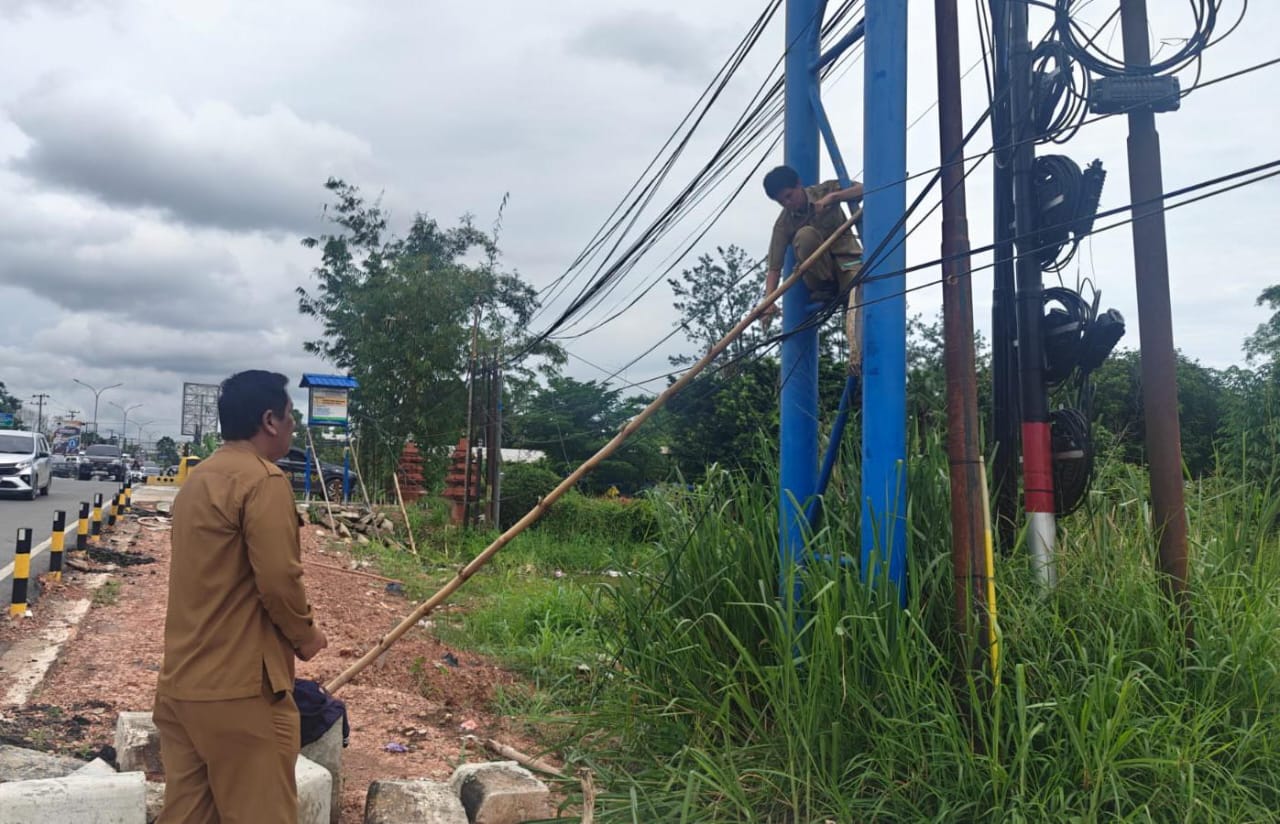 MERAPIKAN : Pemko Banjarbaru didampingi pihak terkait merapikan kabel optik yang menjuntai dan membahayakan pengguna jalan. (Kominfo Banjarbaru untuk Radar Banjarmasin)