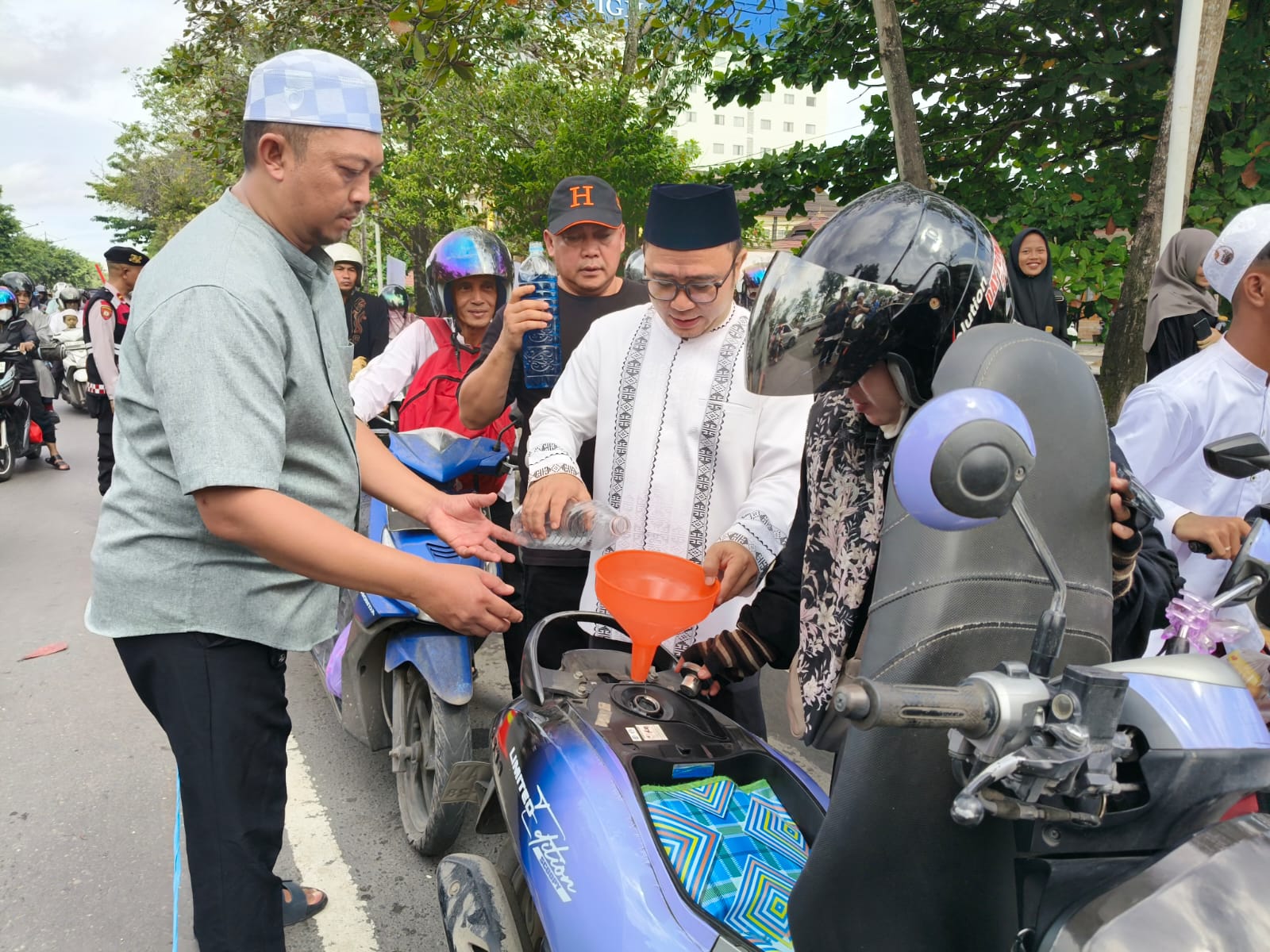 BUAT TRANSPORT:Direktur Utama PT Bangun Banua, H Afrizaldi menuangkan BBM ke motor salah satu jemaah yang akan menuju kegiatan momen 5 Rajab Sekumpul, Martapura, Minggu (28/12/2025).