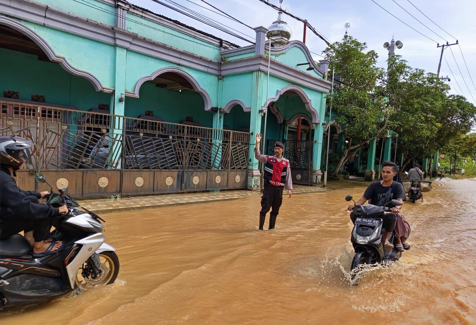 TERENDAM: Anggota Polsek Banjang di Jalan Jermani Husain, Desa Lok Bangkai, HSU, pandu pengendara melewati jalan yang terendam.