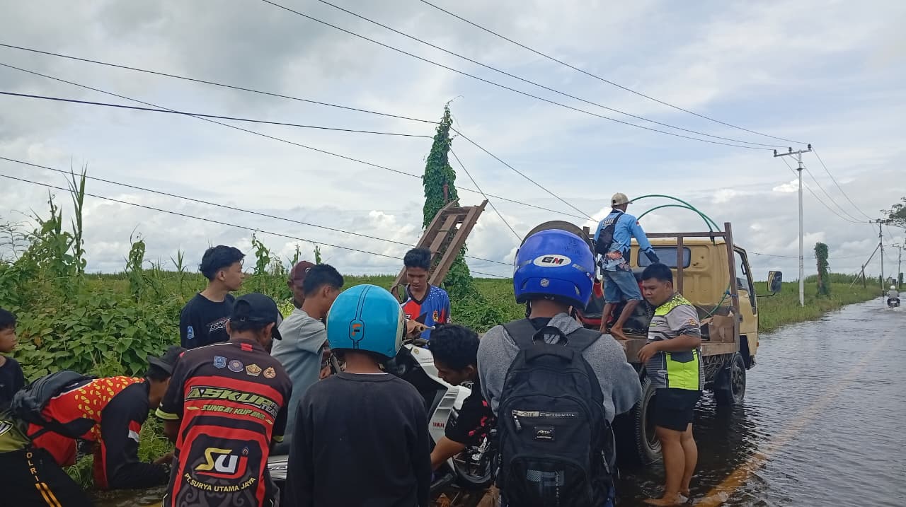 ANGKUT: Beberapa relawan mangangkut motor warga ke atas truk untuk menyeberangi banjir di jalur Kandangan-Nagara.