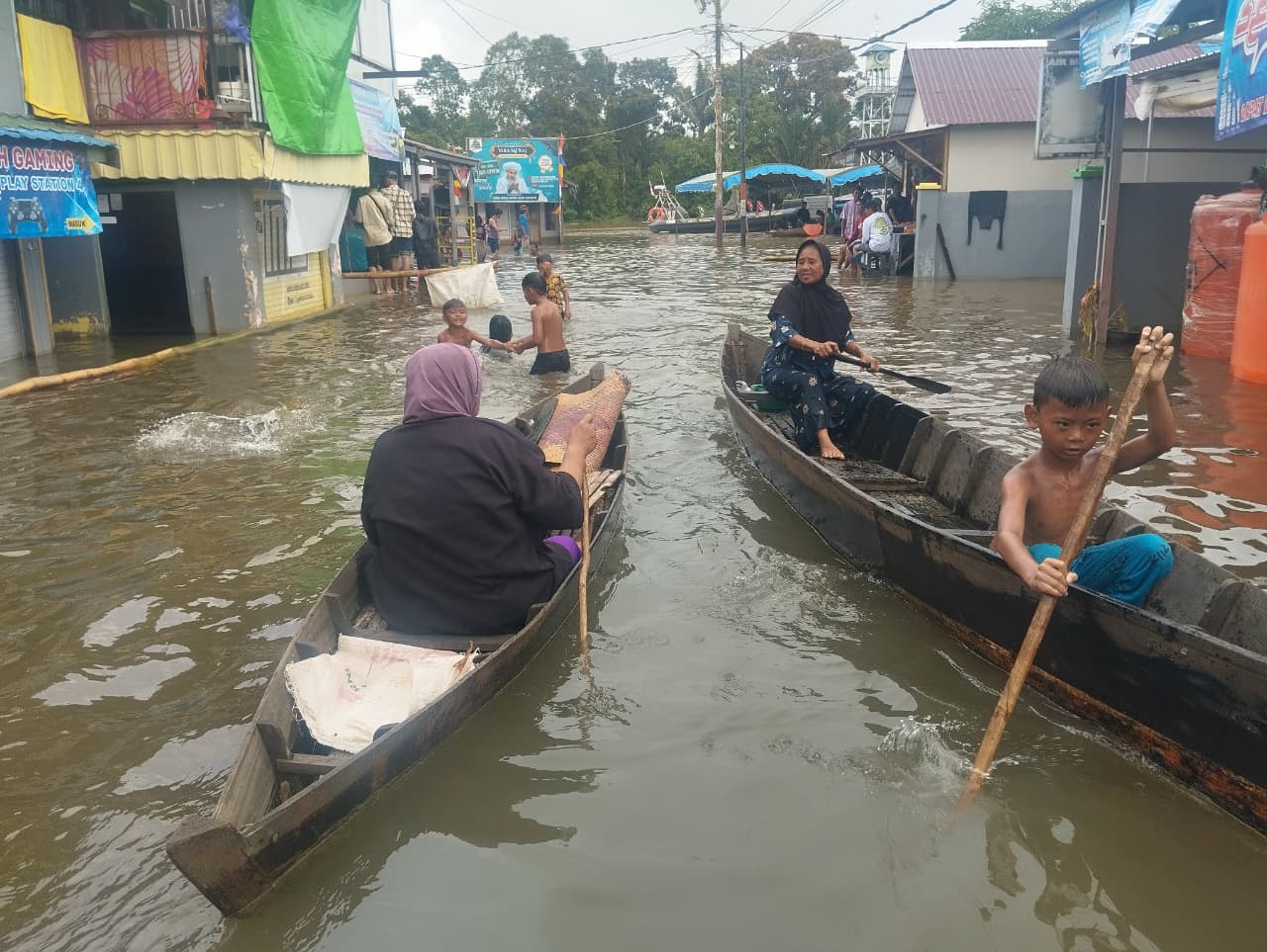 PAKAI SAMPAN: Aktivitas warga Desa Suggai Tabuk Keramat, Kabupaten Banjar di tengah kepungan banjir. Minggu (4/1/2026). Saat ini Pempov menunggu hasil audit lingkungan yang dilakukan KLH.
