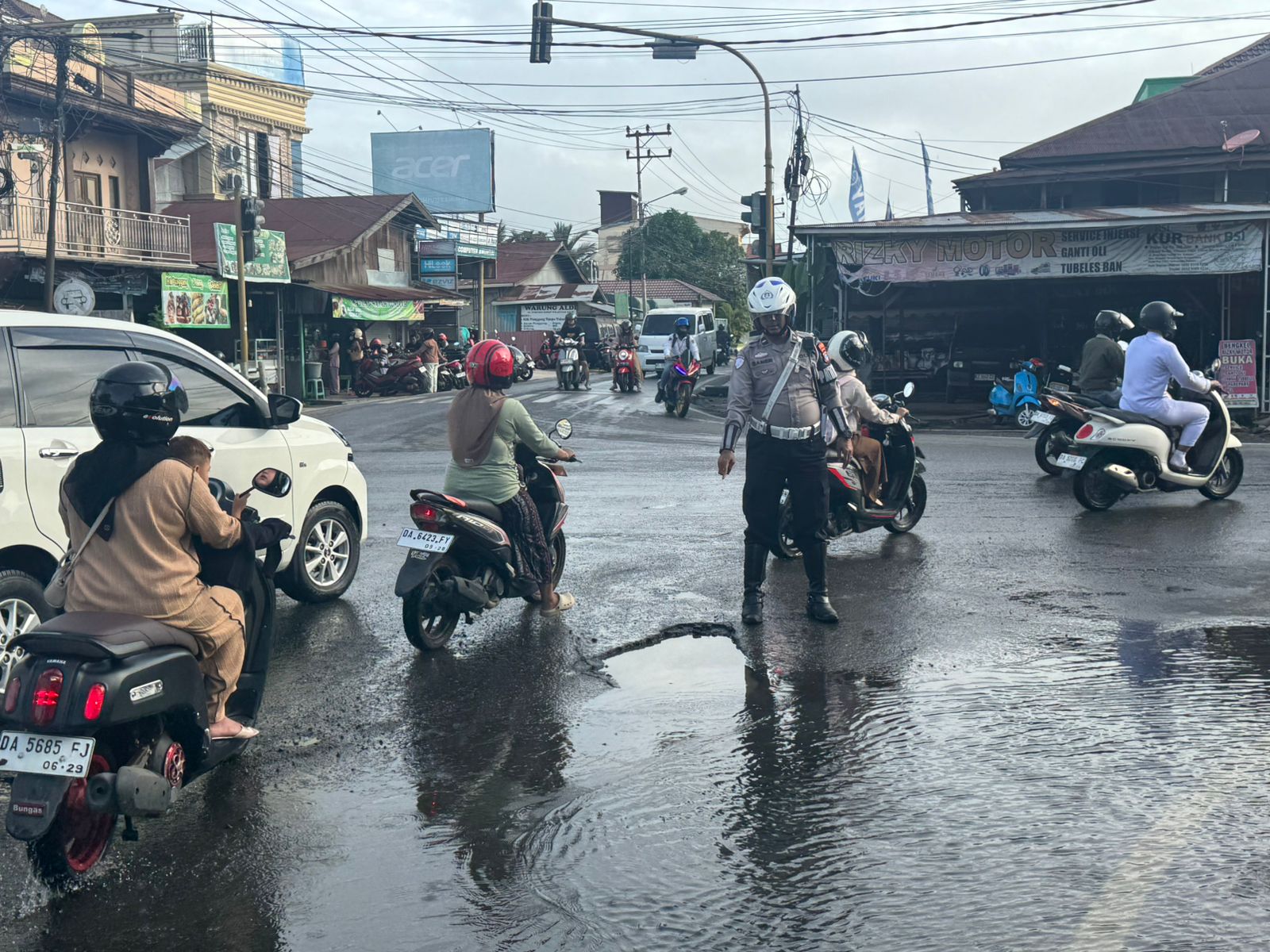 HATI-HATI: Ruas jalan Simpang Empat Palampitan terlihat berlubang, terlihat anggota Satlantas Polres HSU memandu pengendara agar tidak masuk lubang yang bisa menimbulkan lakalantas. (Foto: Istimewa/Ra