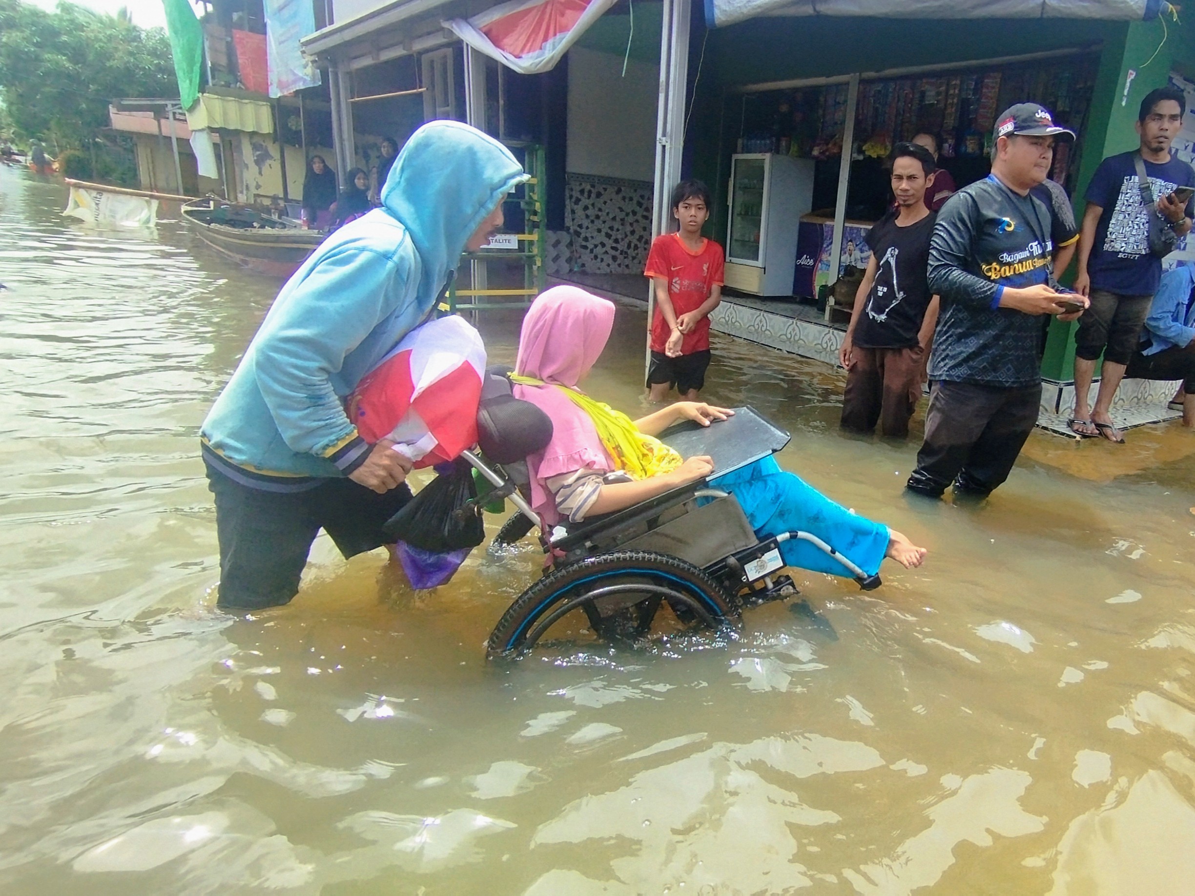 MENDORONG : Warga disalibilitas di Desa Sungai Tabuk Keramat, Kabupaten Banjar, nekat menerjang banjir demi ambil paket bantuan dari Mensos RI pada 4 Januari lalu.